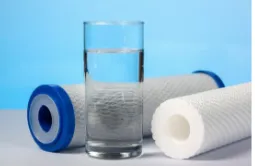 A glass of water is sitting on a table next to two water filters.